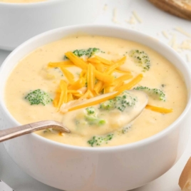 a bowl of Broccoli Cheese Soup topped with cheese with a spoon