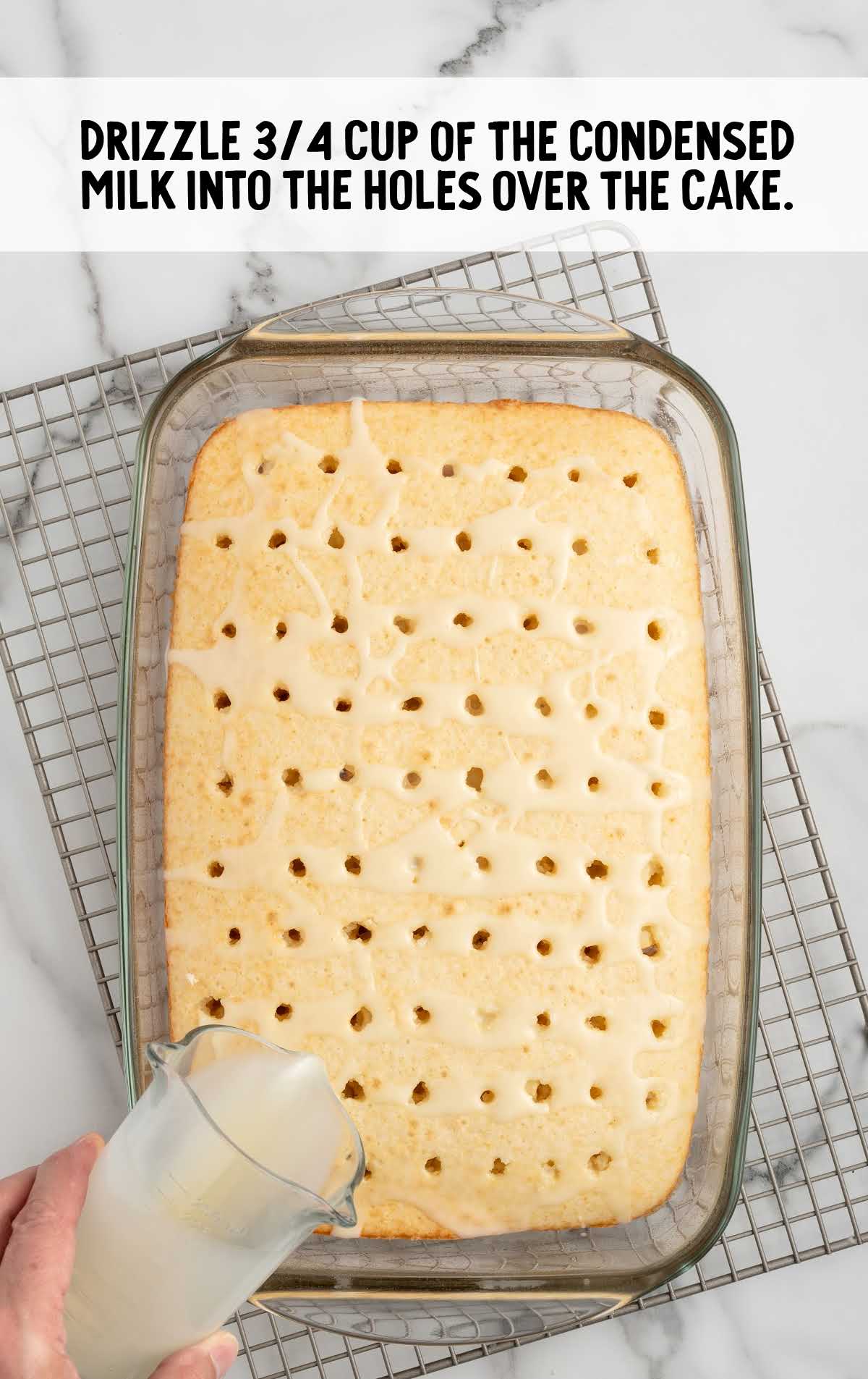 sweetened condensed milk drizzled over the cake with holes in it