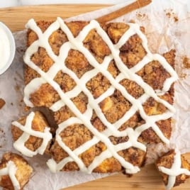 Cinnamon Pull Apart Bread on a wooden board with a bowl of cream cheese frosting