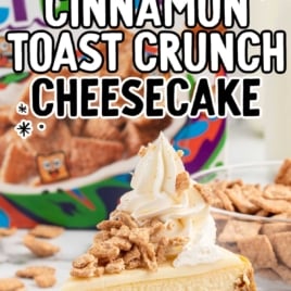 a slice of Cinnamon Toast Crunch Cheesecake topped with whipped topping and cinnamon toast crunch cereal crumbs on a plate