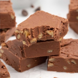 A close up shot of Fantasy Fudge Recipe stacked on top of each other with one having a bite taken out of it