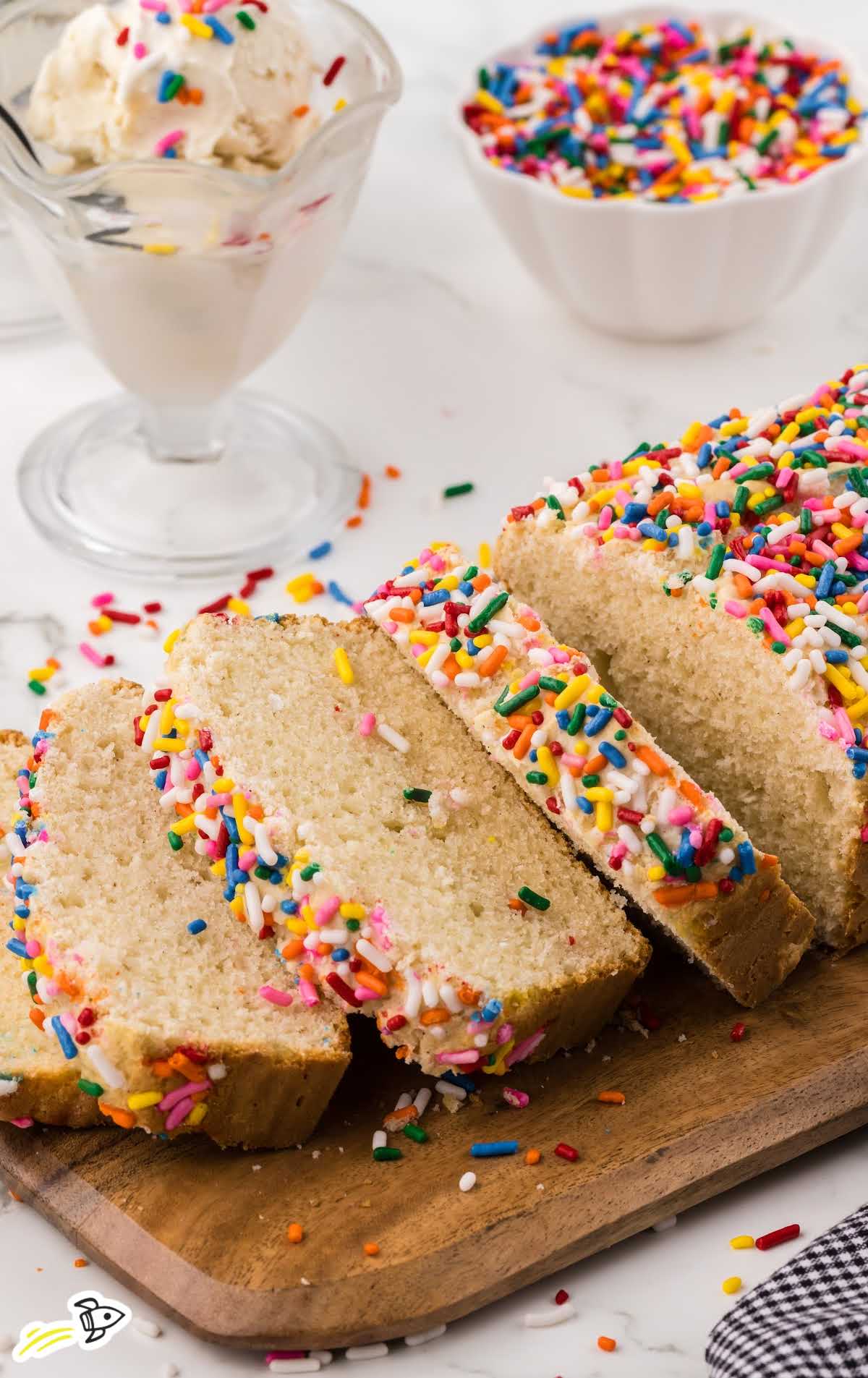 a loaf of Ice Cream Bread with some slices on a plate on a wooden board