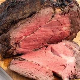 a cooked prime rib sliced on a wooden board