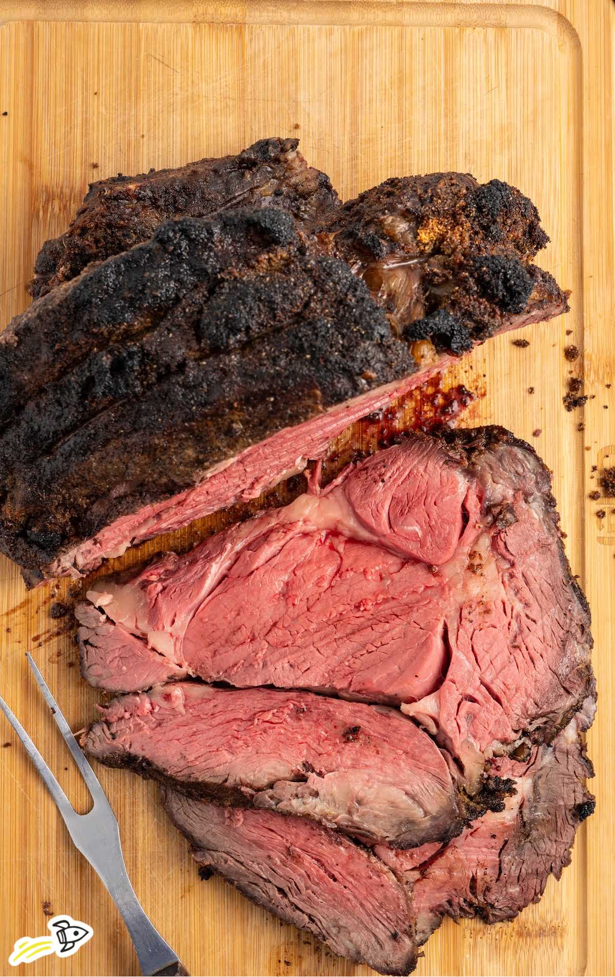 a cooked prime rib sliced on a wooden board