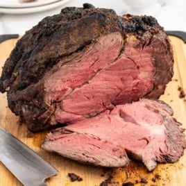 a cooked prime rib sliced on a wooden board