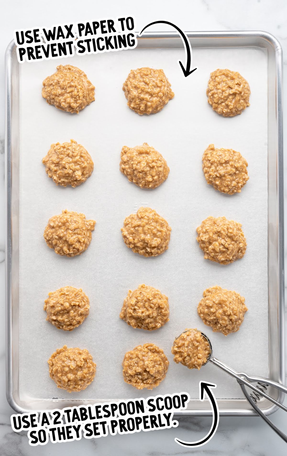 Unbaked peanut butter no-bake cookies scooped onto a wax paper-lined baking sheet with a cookie scoop, showing tips to use wax paper and a 2-tablespoon scoop for best results.