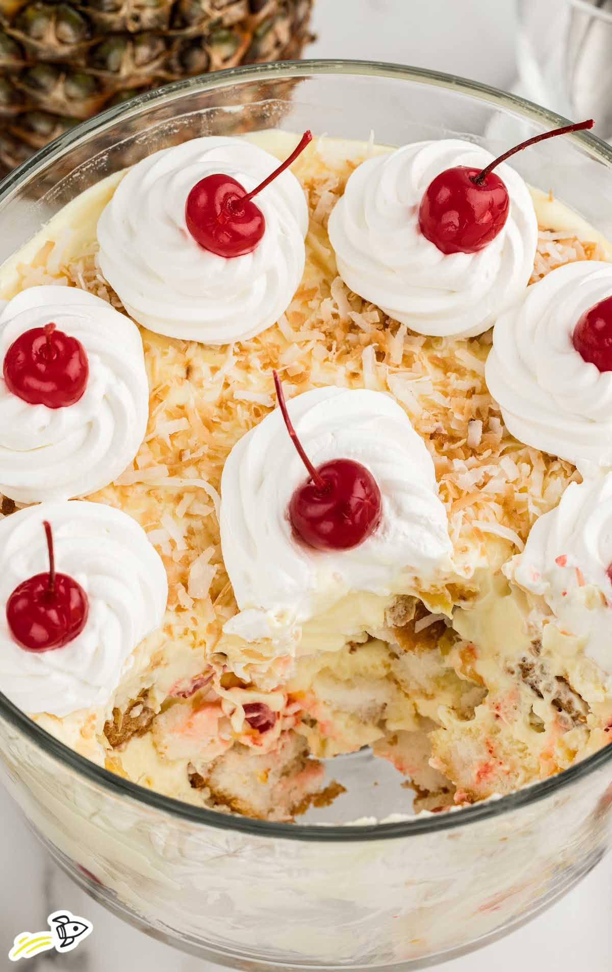 Pina Colada Trifle topped with whipped topping and cherries in a jar