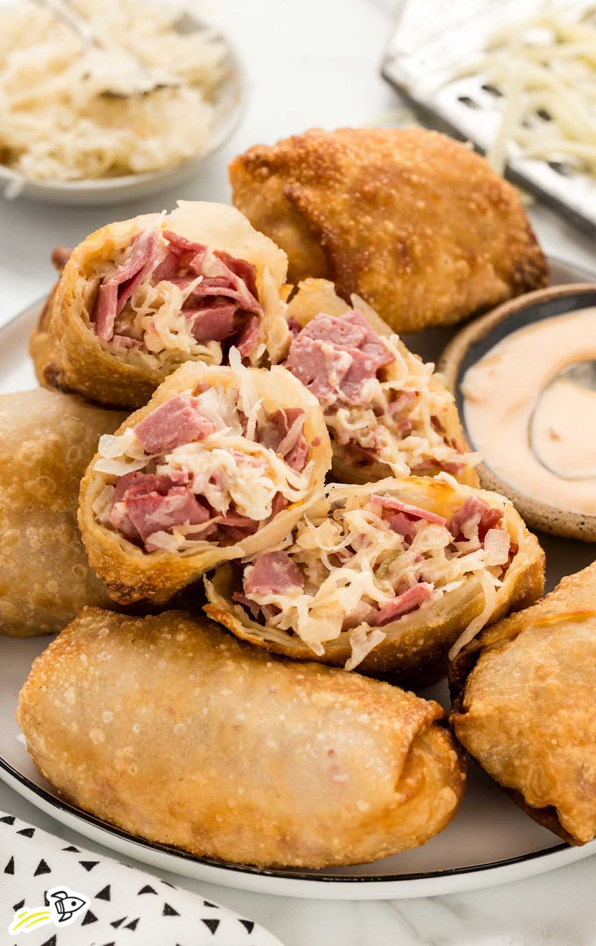 Reuben Eggrolls with a bowl of thousand island dressing on a plate