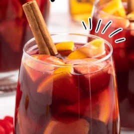 a glass of Sangria garnished with sliced fruit and cinnamon sticks
