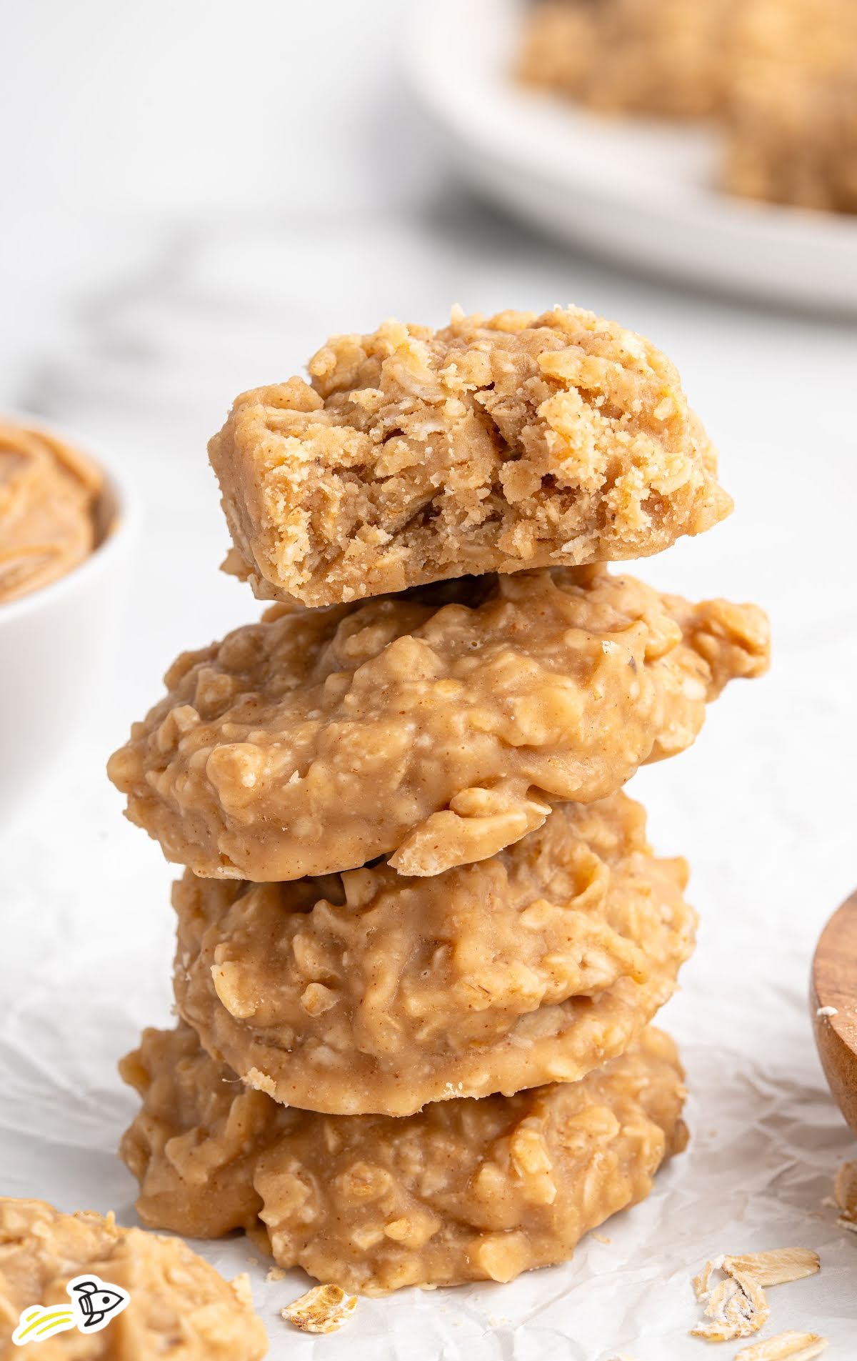 Stack of no-bake peanut butter cookies with the top cookie broken in half to reveal the soft, chewy texture inside.