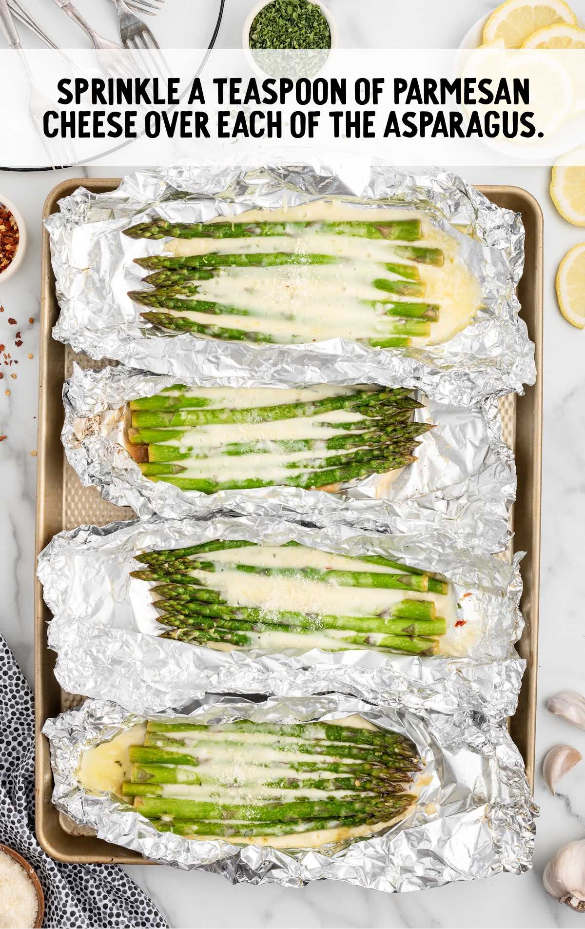 grated parmesan cheese sprinkled over the asparagus on a baking sheet