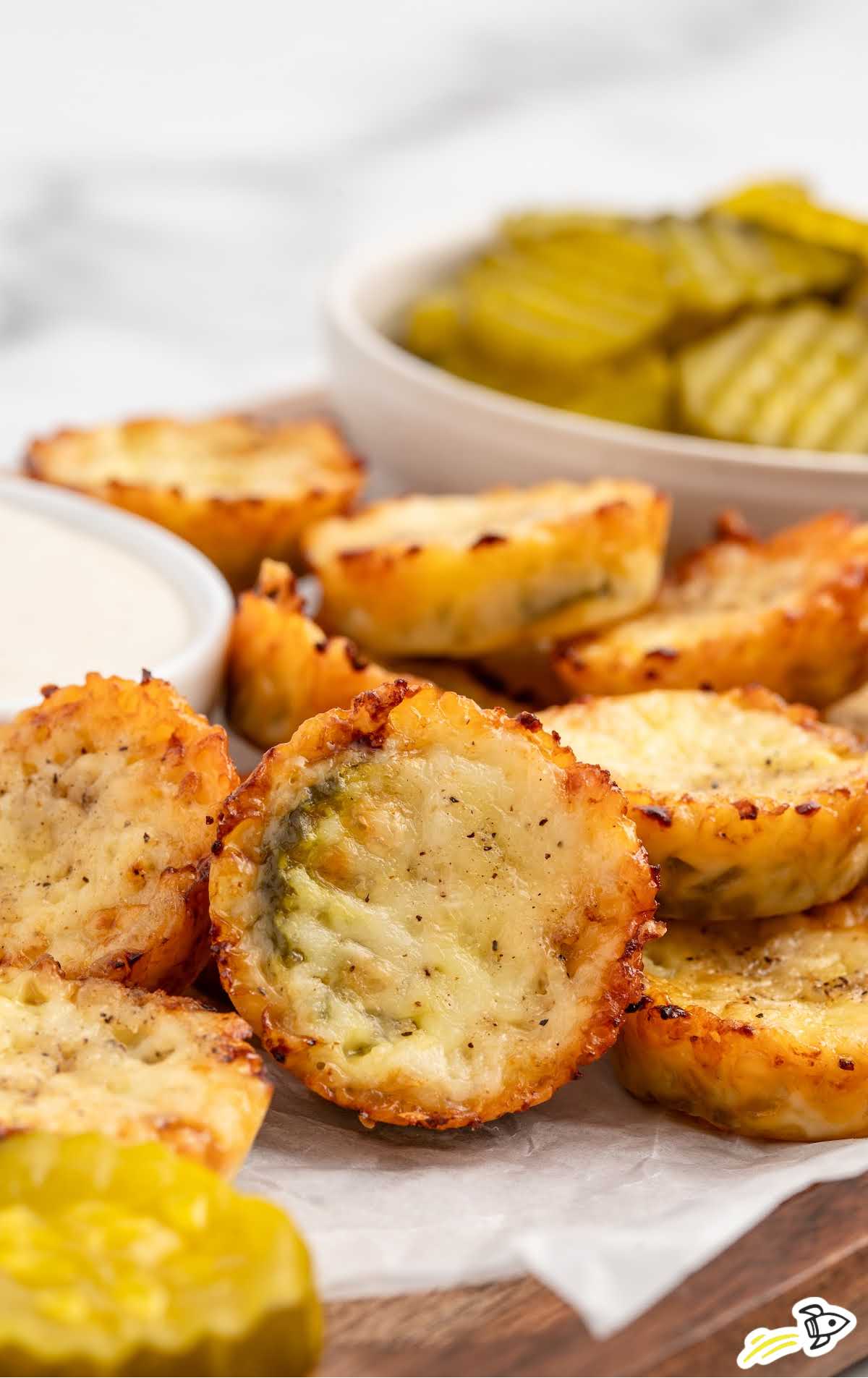 a plate of Fried Pickles with a bowl of sauce and a bowl of pickles