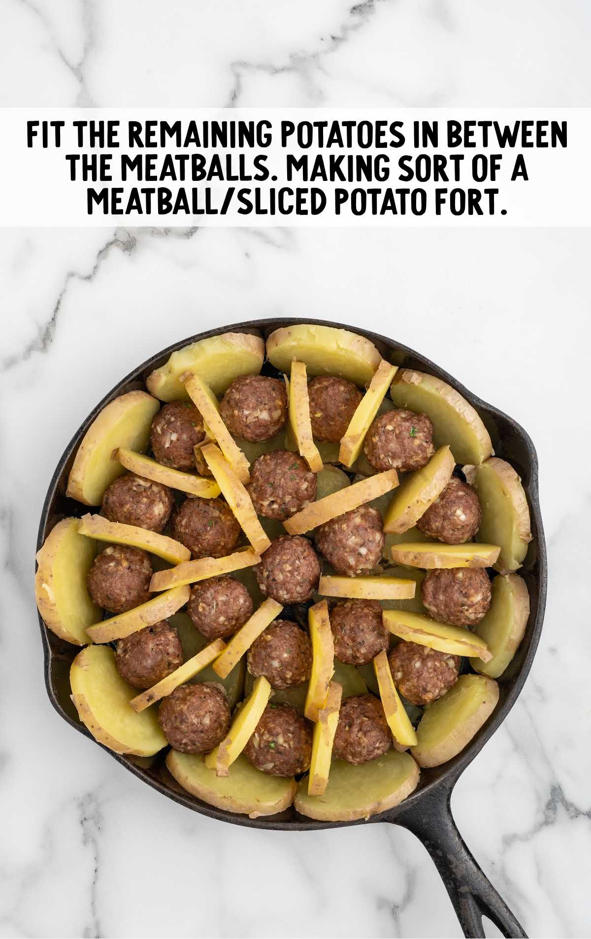 sliced potatoes placed in the middle of the meatballs in the skillet