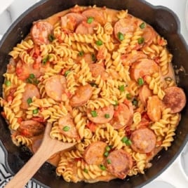 a skillet of Kielbasa pasta garnished with green onions