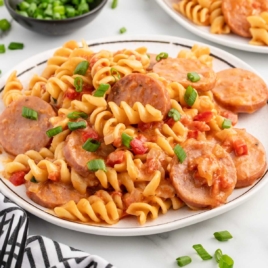 a plate of Kielbasa pasta garnished with green onions