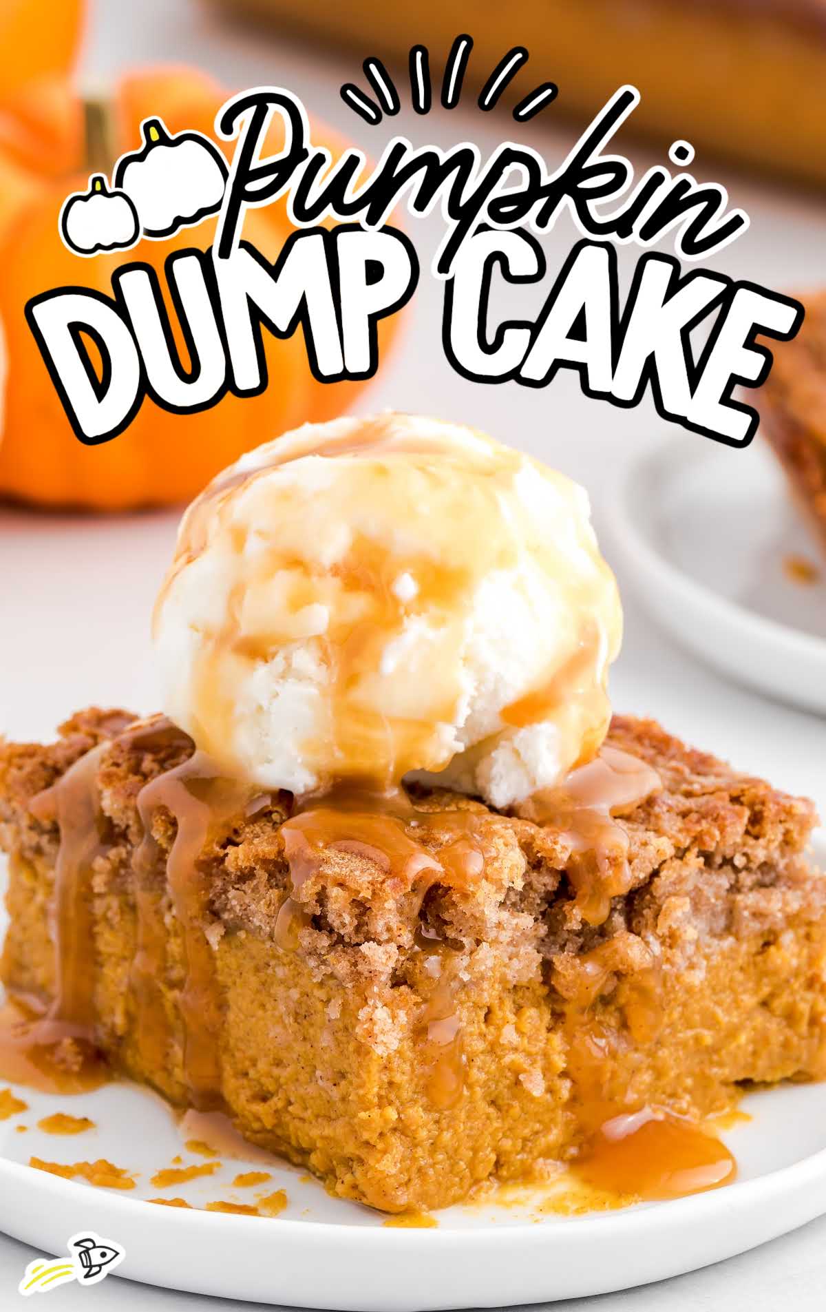 Pumpkin dump cake slice with vanilla ice cream and caramel sauce in front of small pumpkins.