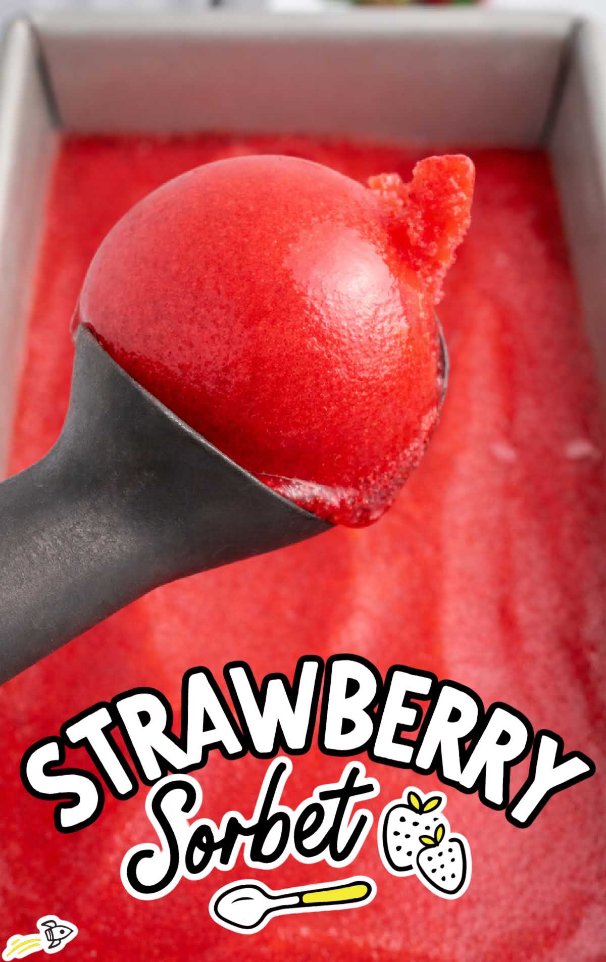 Ice cream scoop lifting a smooth, glossy scoop of strawberry sorbet from a loaf pan.