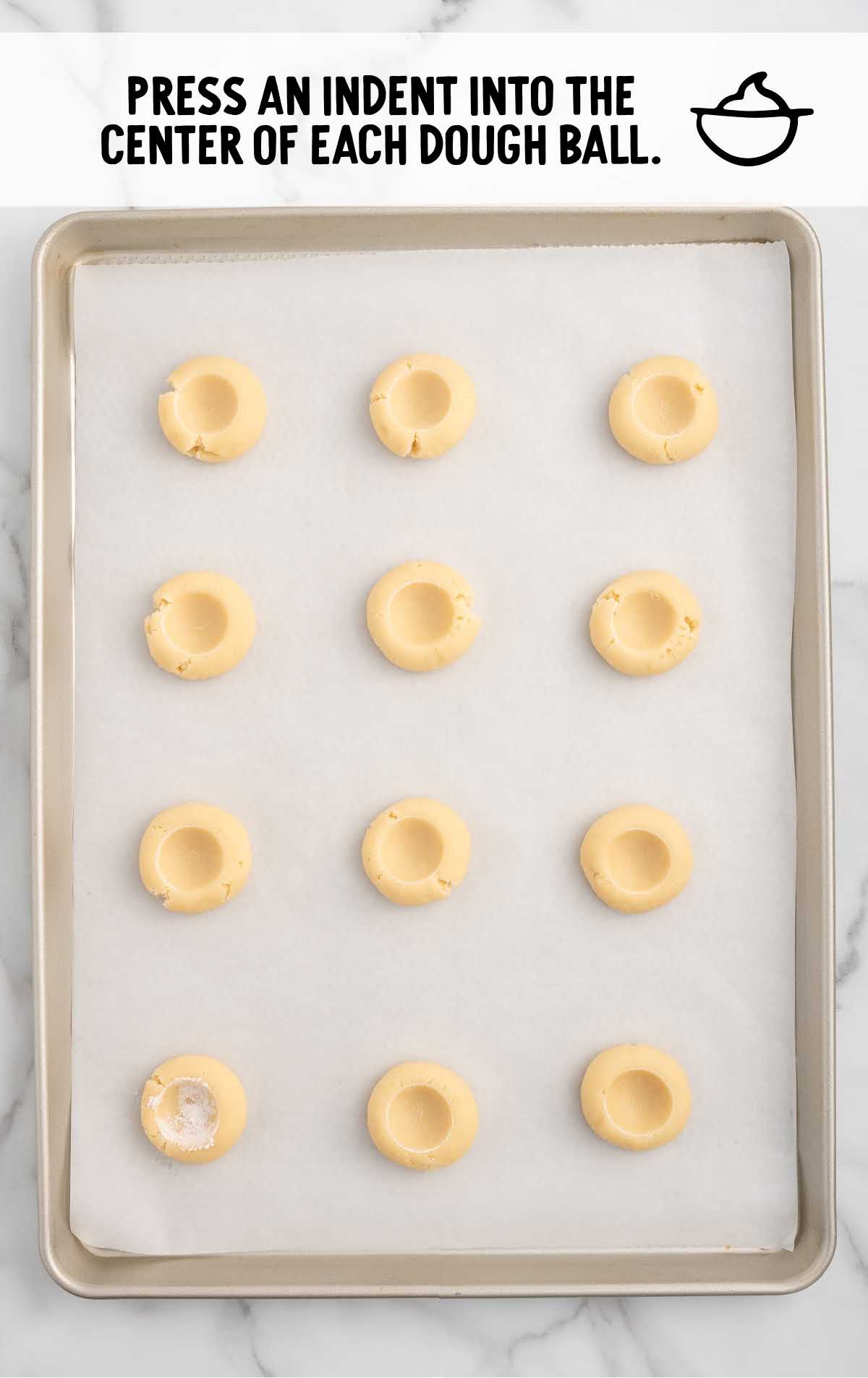 indent pressed into the middle of each cookie dough ball on a baking sheet