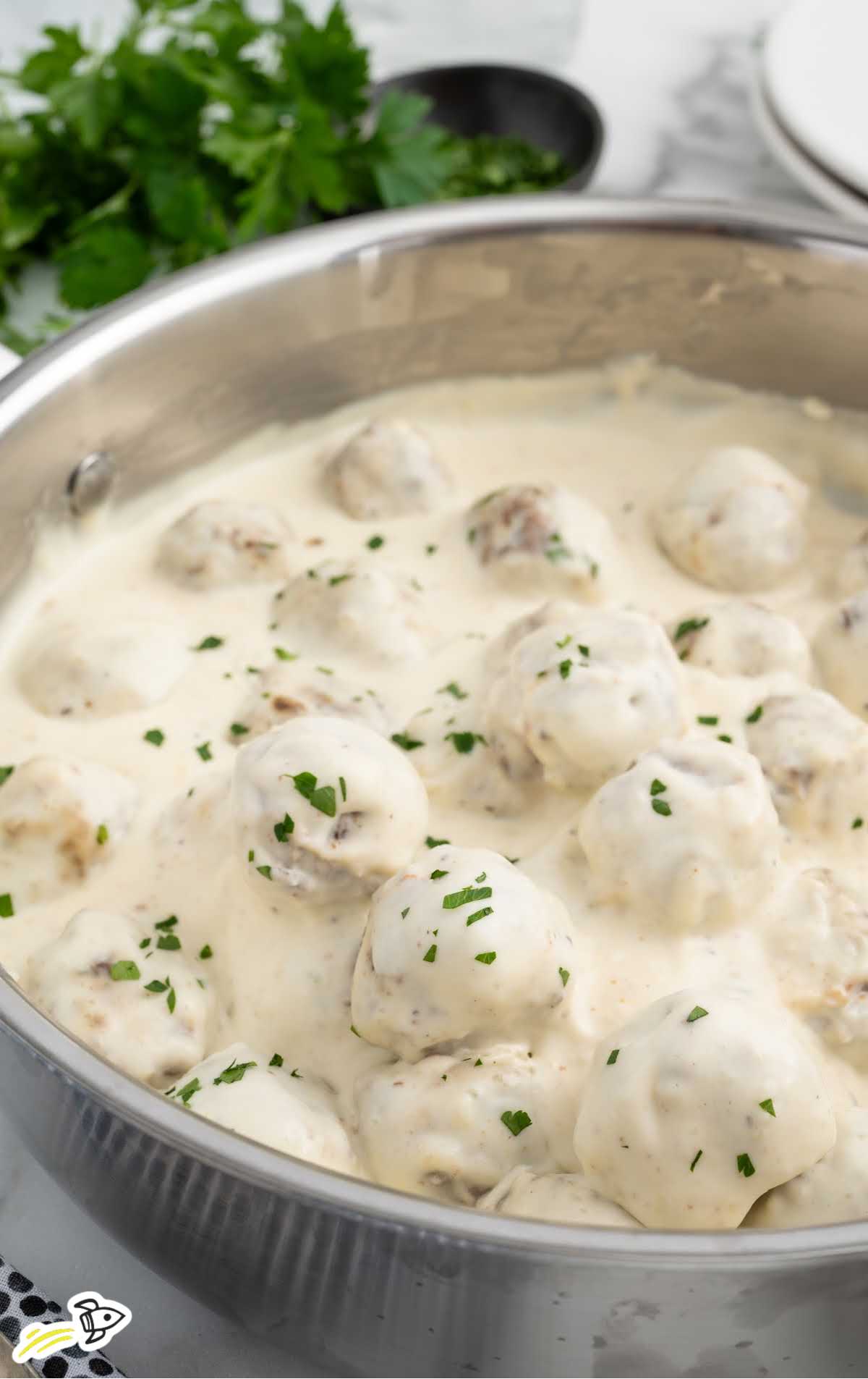 a pot of Alfredo Sauce with Meatballs garnished with parsley