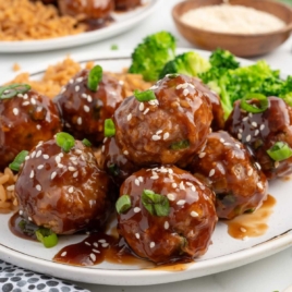 a plate of Asian Turkey Meatballs garnished with green onions and sesame seeds served with rice and broccoli