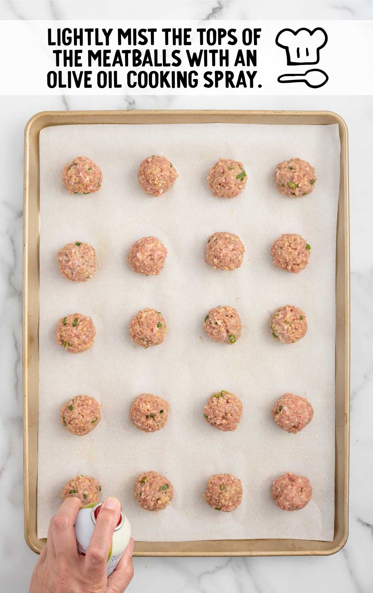 meatballs sprayed with olive oil on a baking sheet