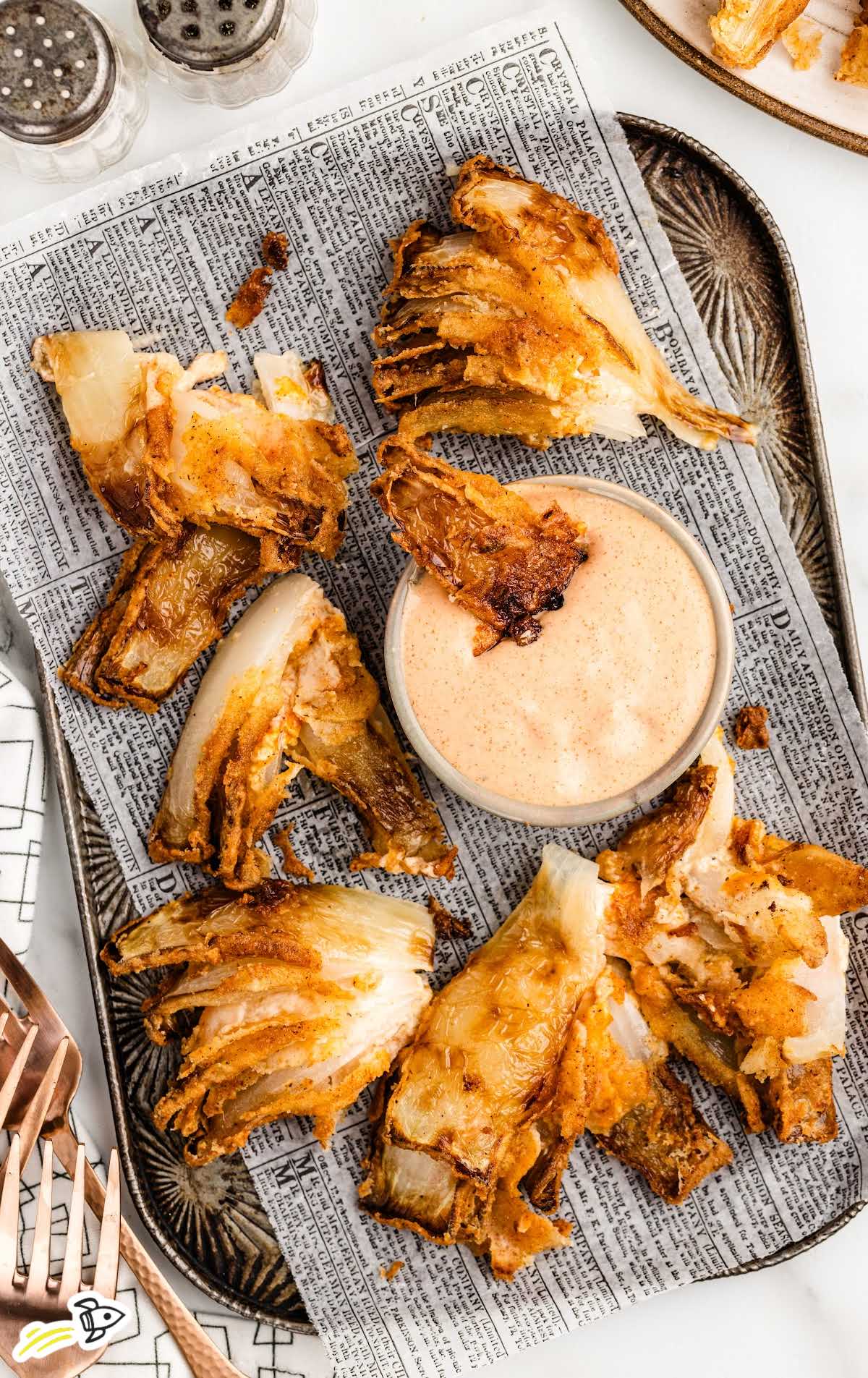 a plate of Awesome Blossom with a bowl of dipping sauce