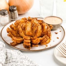 a plate of Awesome Blossom with a bowl of dipping sauce