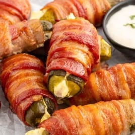 a bunch of Bacon Wrapped Pickles with a bowl of dipping sauce