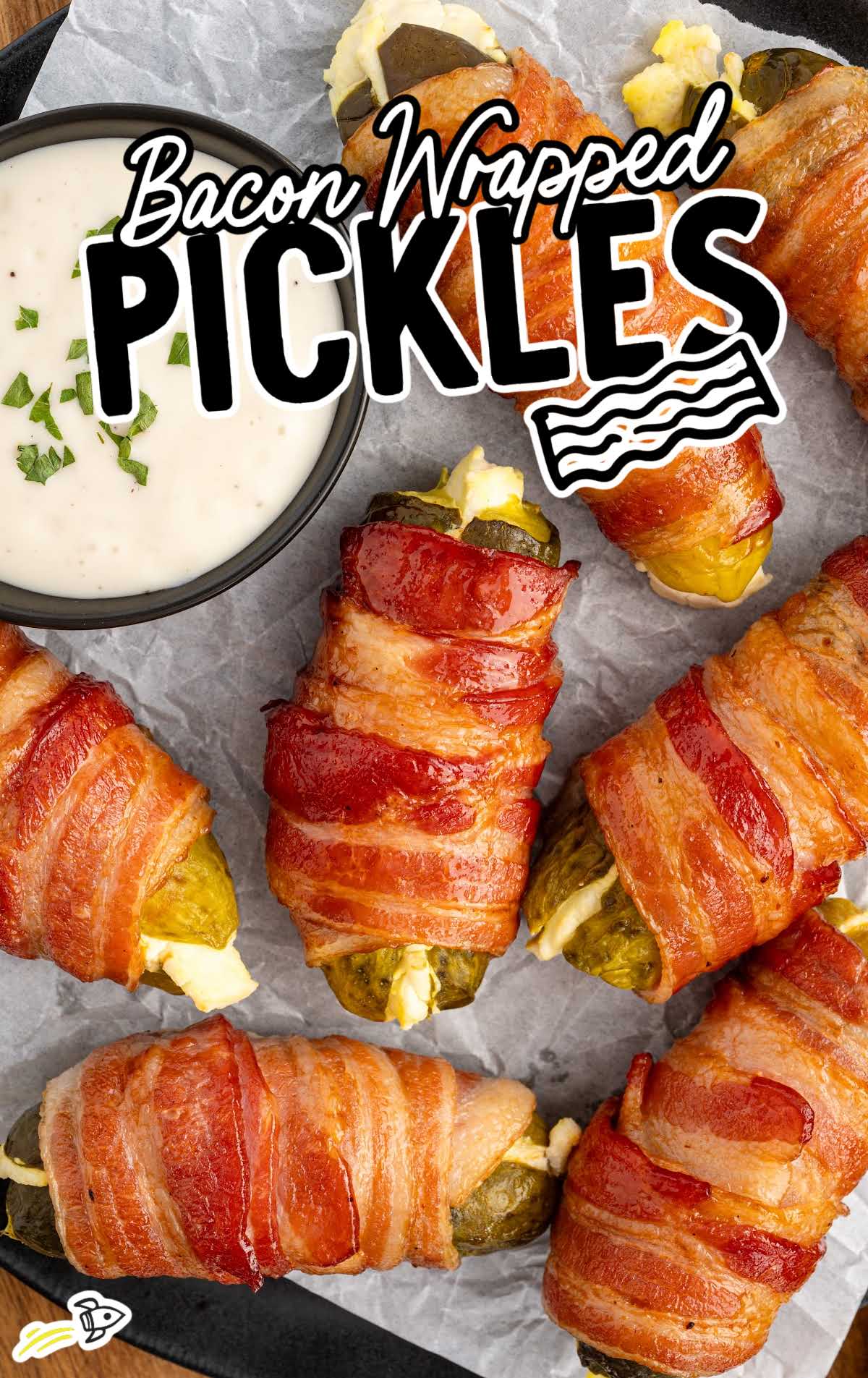 a bunch of Bacon Wrapped Pickles with a bowl of dipping sauce