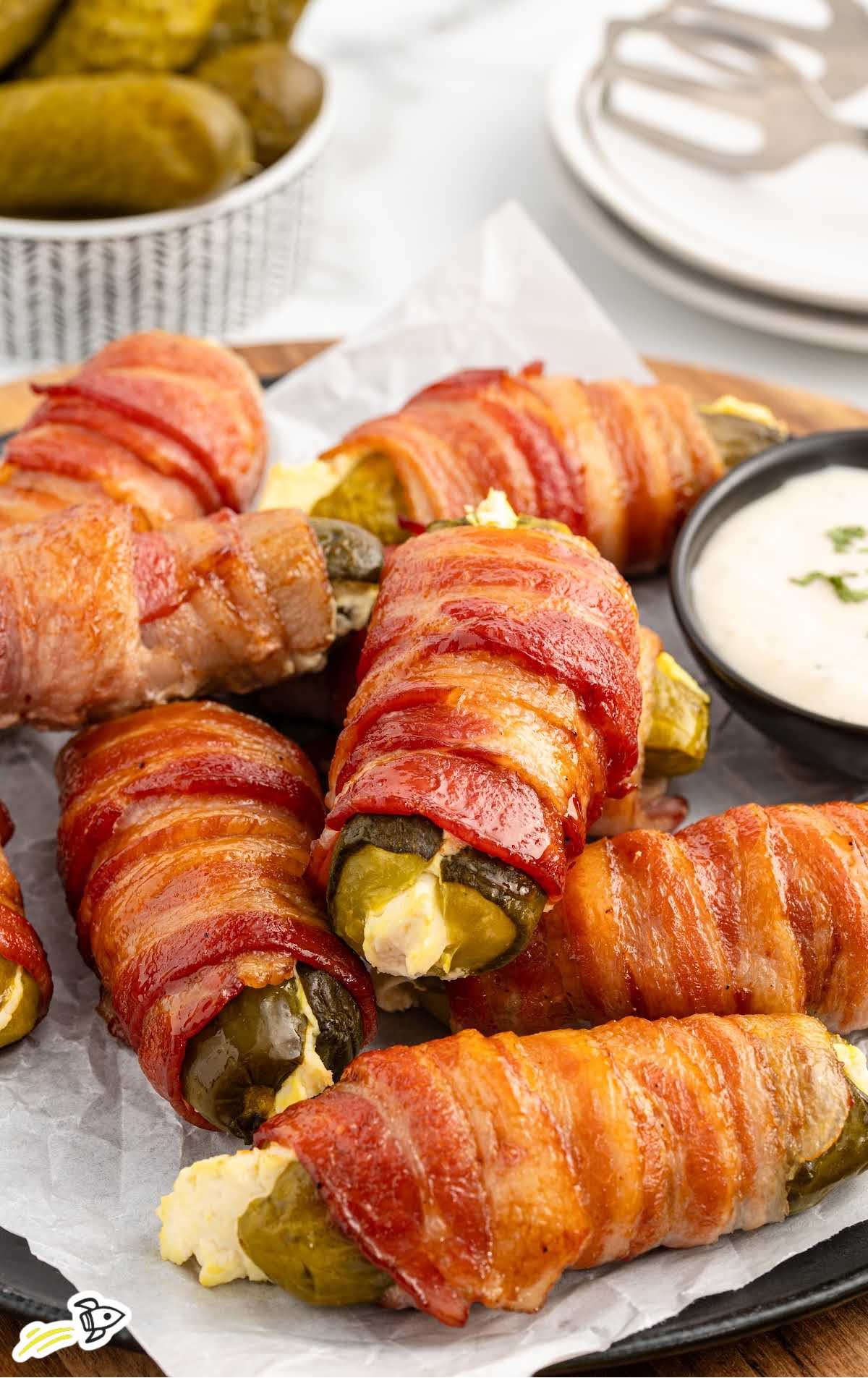 a bunch of Bacon Wrapped Pickles with a bowl of dipping sauce