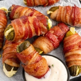 a bunch of Bacon Wrapped Pickles with a bowl of dipping sauce