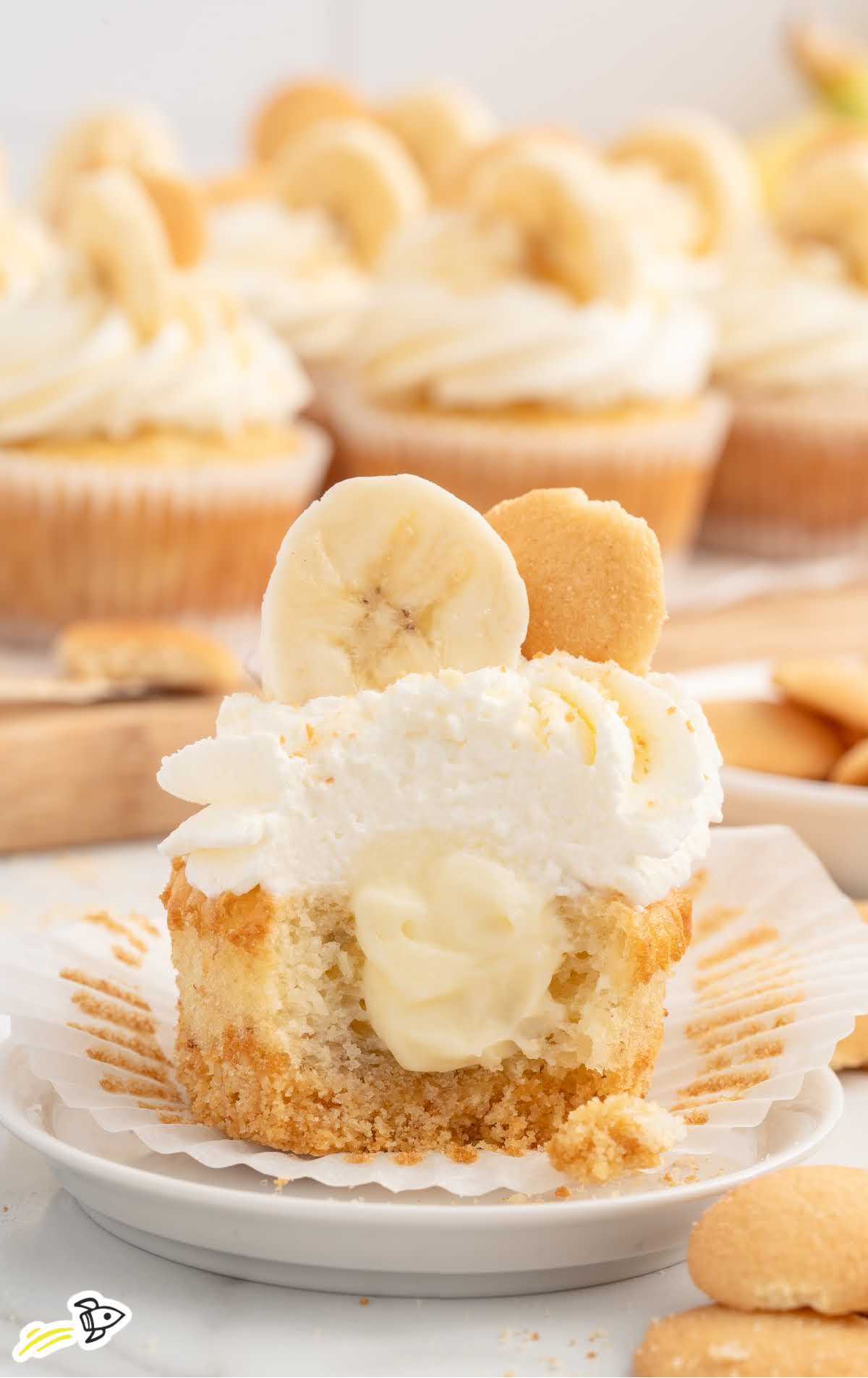 a Banana Pudding Cupcake topped with frosting, a slice of banana, and a vanilla wafer