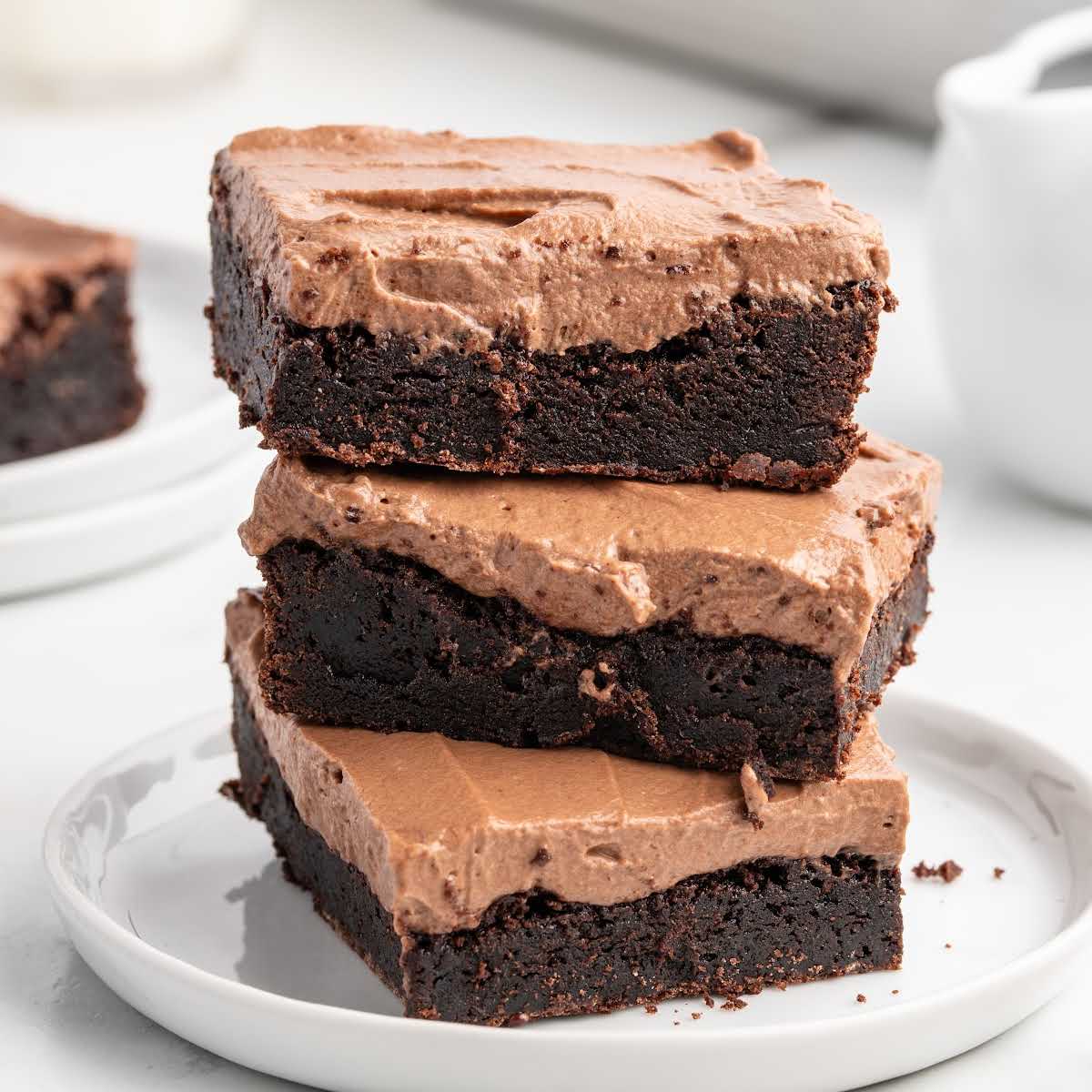Stack of chocolate mousse brownies on a white plate with creamy mousse topping