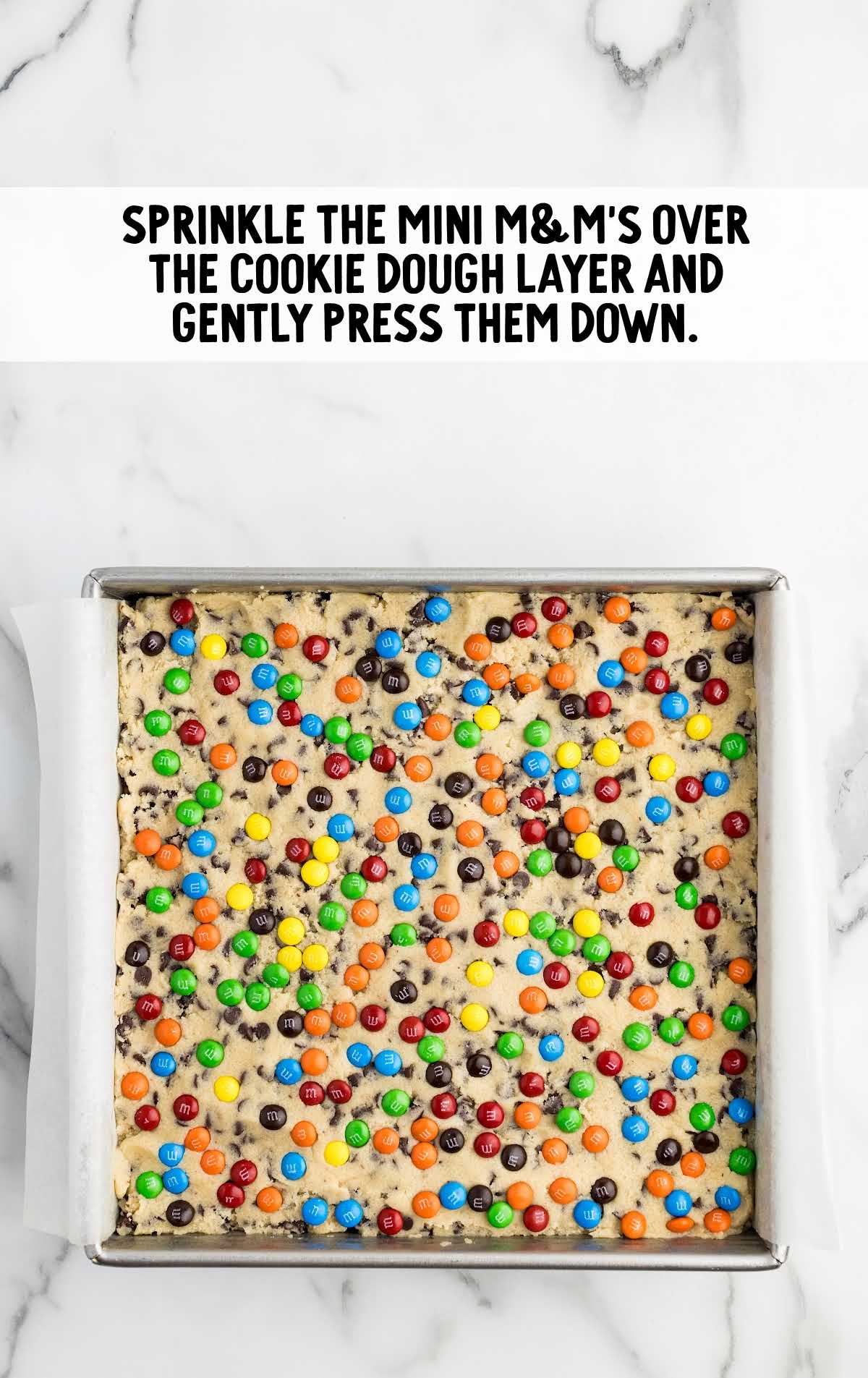 mini m&ms sprinkled on top of the cookie dough