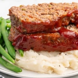 meatloaf served with mashed potatoes and green beans on a plate