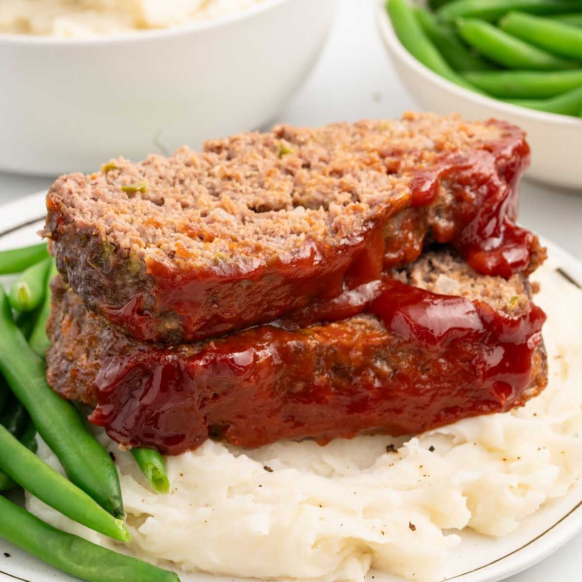 meatloaf served with mashed potatoes and green beans on a plate