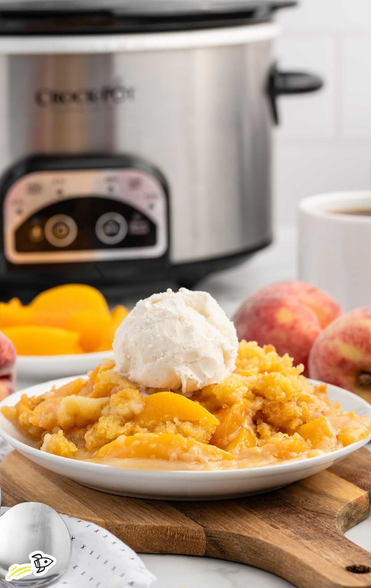 a serving of Peach Dump Cake topped with vanilla ice cream on a plate