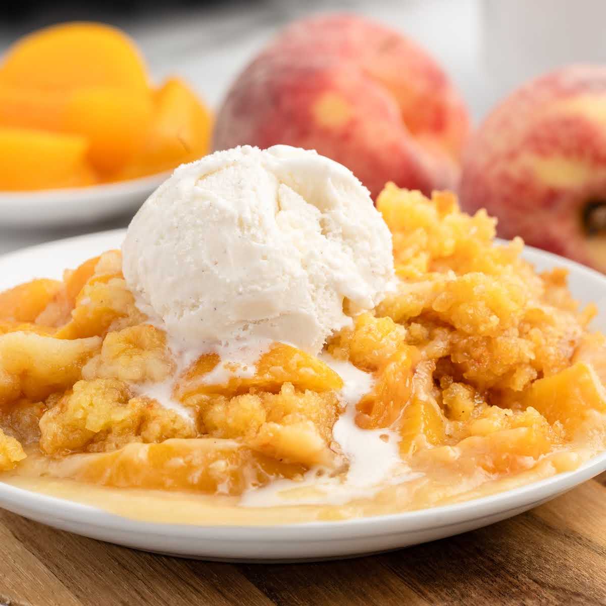 a serving of Peach Dump Cake topped with vanilla ice cream on a plate