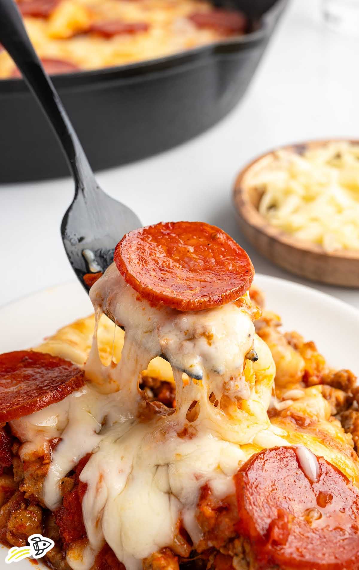 Close-up shot of cheesy crustless pizza being served with a black spoon, melted cheese stretching from skillet to plate.