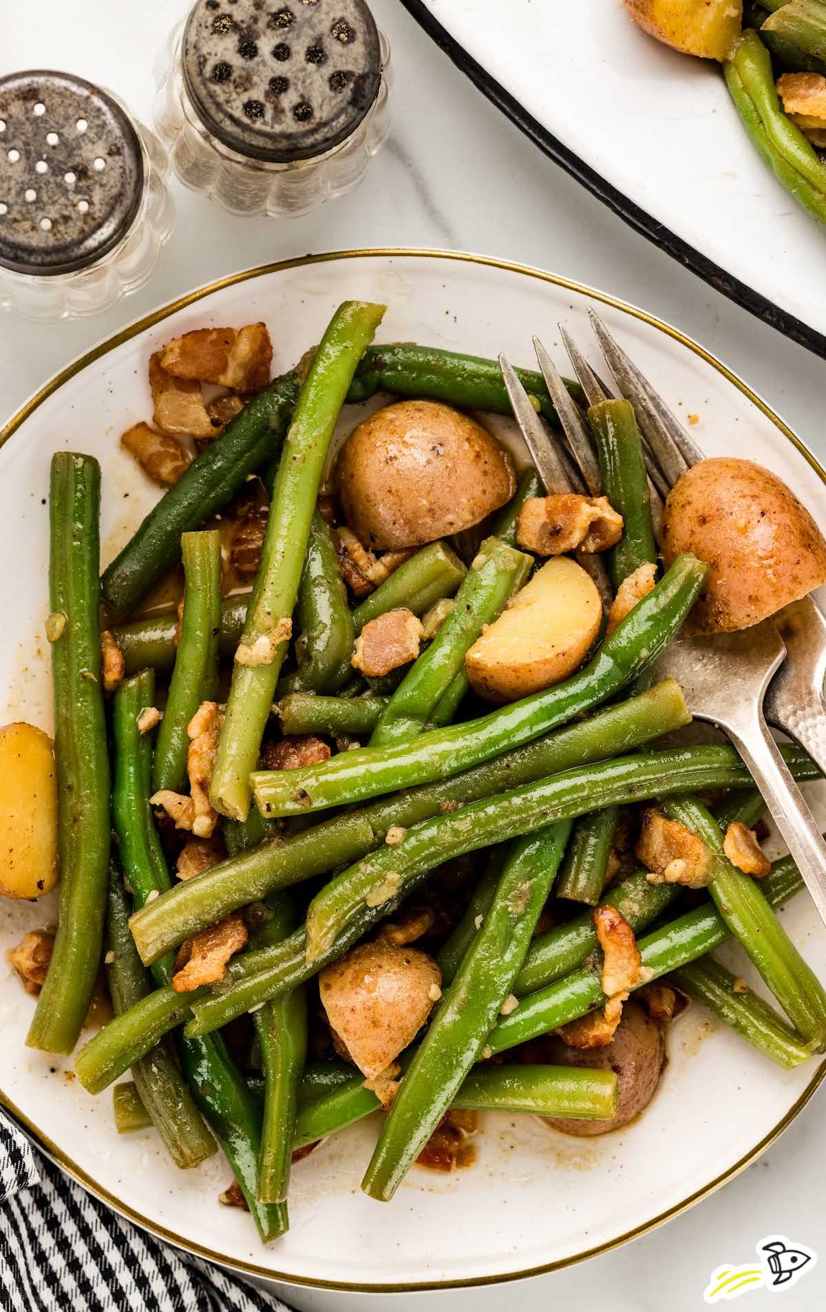 a plate of green beans and potatoes with a fork