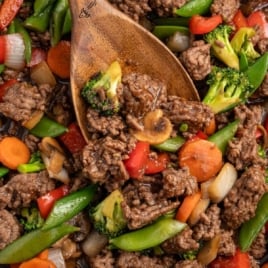 Overhead view of ground beef stir fry in skillet with broccoli, carrots, bell peppers, and mushrooms.