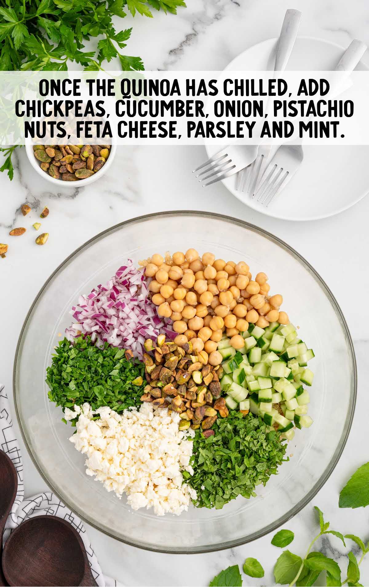 chickpeas, diced cucumber, diced red onion, chopped pistachio nuts, crumbled feta cheese, fresh parsley, and fresh mint added to the quinoa in the bowl