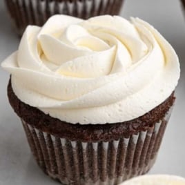 Chocolate cupcake decorated with piped marshmallow frosting swirl in rose design