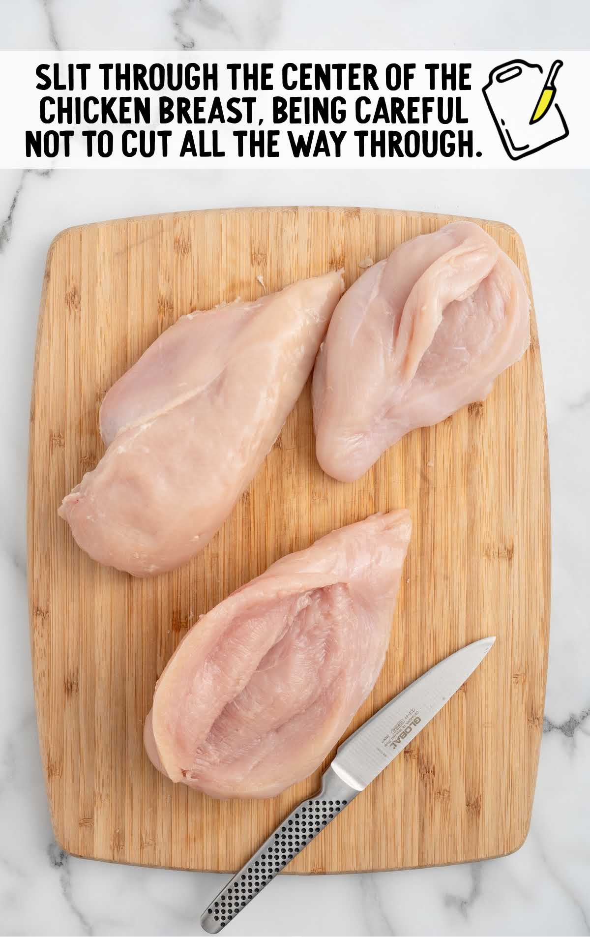 chicken breast sliced through the center on a wooden cutting board