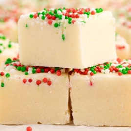 Sugar Cookie Fudge with christmas sprinkles stacked on top of each other