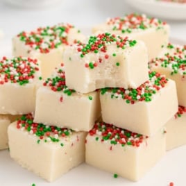 Sugar Cookie Fudge with christmas sprinkles stacked on top of each other