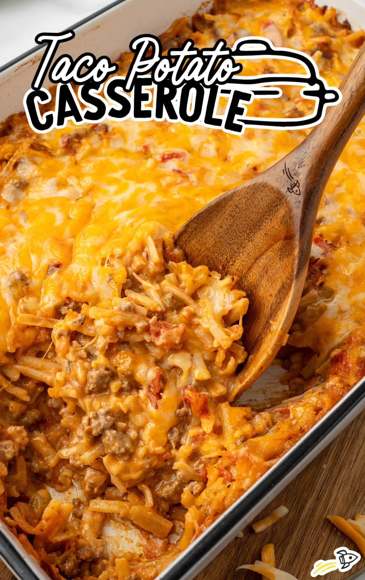 a baking dish of Taco Potato Casserole with a large wooden spoon