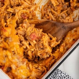 a baking dish of Taco Potato Casserole with a large wooden spoon