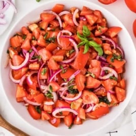 a bowl of Tomato and Onion Salad topped with basil