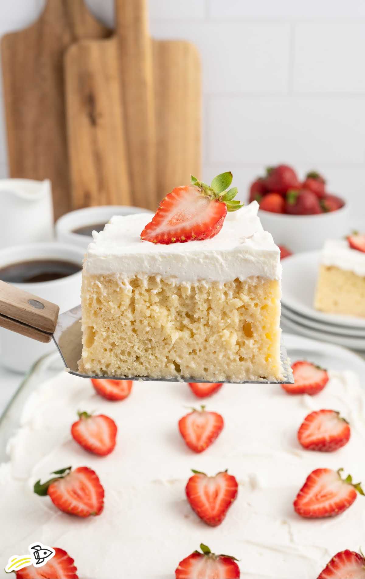 a slice of Tres Leches Cakes topped with a slice of strawberry on a spatula